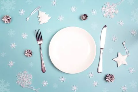 Winter festive table setting with cutlery and white decorations on blue table Stock Photos