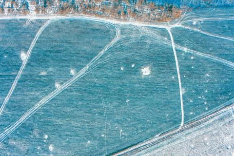 Winter field with tree line and frozen dirt road top view of snow covered Stock Photos