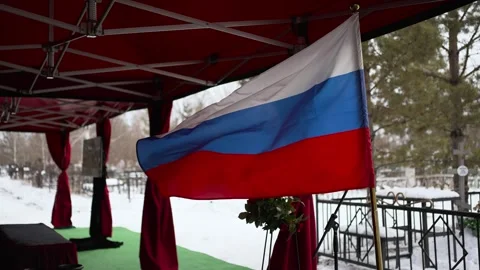 In winter, a flag with red, white and blue flowers flies at the cemetery. Stock Footage 306493546