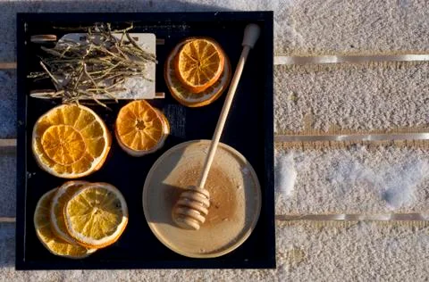 Winter flat lay with dry orange, honey with wooden spoon, toy sled with Rhodo Stock Photos