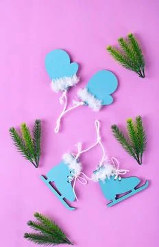 Winter flat lay with small ice skates and mittens on pink 스톡 사진
