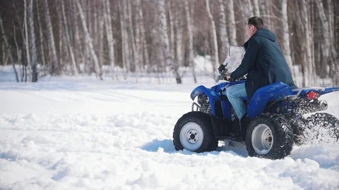 A winter forest in daylight. Cold weather. An adult man riding a big snowmobile Stock Footage 106887262