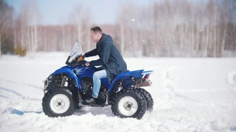 A winter forest in daylight. A man riding a big blue snowmobile Stock Footage 106886162