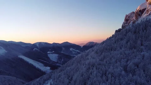 A winter forest on the edge of a rocky mountain illuminated by the setting sun 動画素材 227712804