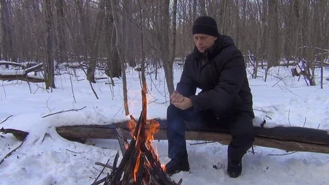 In the winter forest a lone man warms his hands by the fire Stock Footage 122517185