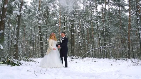 Winter forest shot of young couple having fun under snowfall. Slow motion Stock Footage 83019613