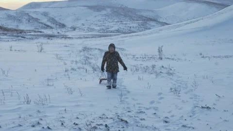 Winter fun for children. A boy whose clothes are in the snow with a sled at the Stock Footage 150567240