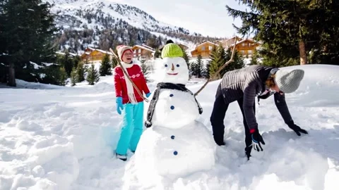 Winter fun, happy kid and mother playing with snowballs and snowman. Stock Footage 144248093