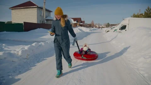 Winter fun scene: mother drags child on sled through snow Stock-Footage 334838291
