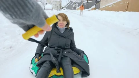 Winter fun. someone is taking a smiling woman on an inflatable sleigh from the Stock Footage 150550856