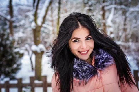 Winter. Girl brunette capless smiles on the background of snow. Close-up Stock Photos