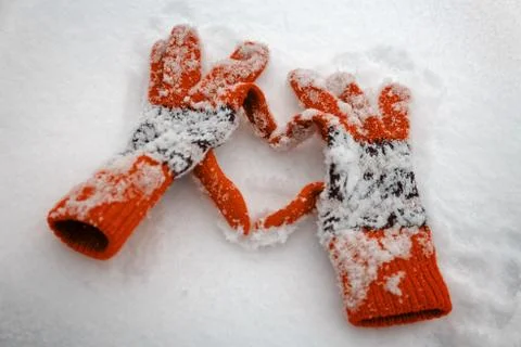 Winter gloves make the shape of a heart on a snow. Stock Photos