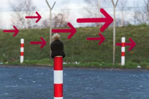 Winter hat in front of red arrows on a fence Foto stock