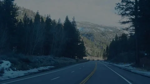 Winter highway curving through pine forest with snowy Sierra... Stock Footage 328254660