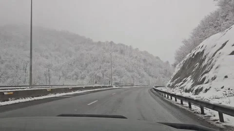 Winter highway view through car windshield, snowy hills stretching Stock Footage 329783321