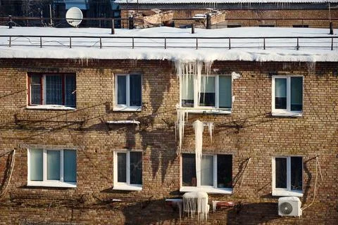Winter ice and icicles on old brick wall, urban decay scene Stock Photos