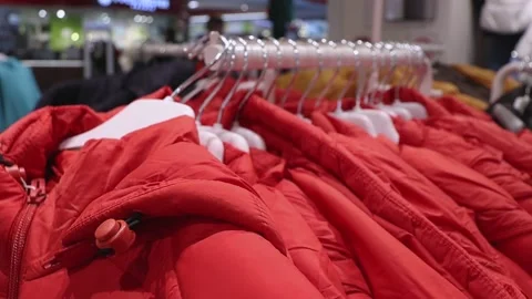 Winter jacket in a sport store. Red jackets on hangers Stock Footage 219424667