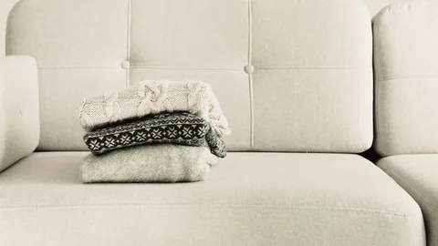 Winter jumpers being stacked on the sofa Stock Footage 84150819