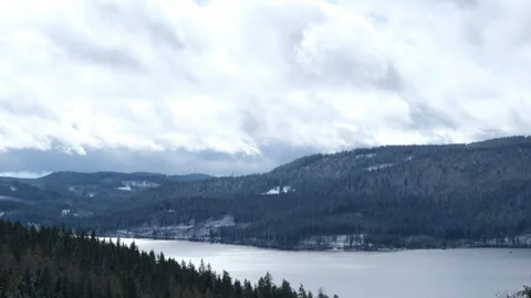 The winter lake between the mountains covered with snowy forest Stock Footage 266653283