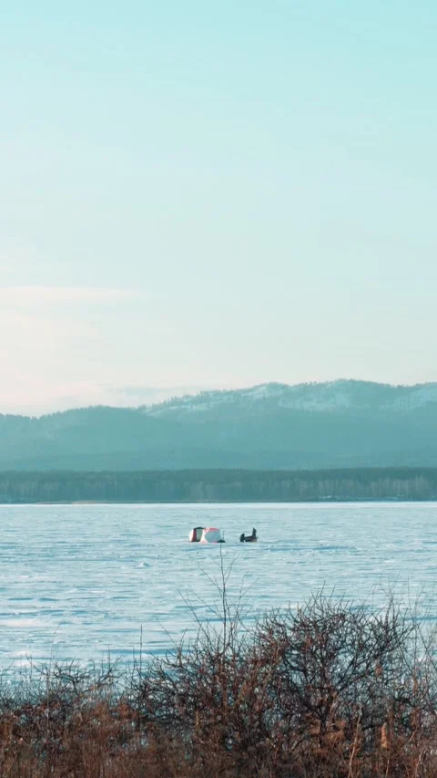 Winter landscape overlooking a lake where fishermen fish in winter tents. Stock Footage 299975508