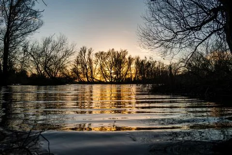 Winter landscape of a setting sun shining through the trees Stock Photos
