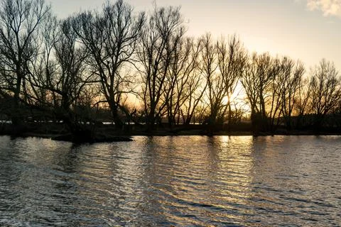 Winter landscape of a setting sun shining through the trees Stock Photos