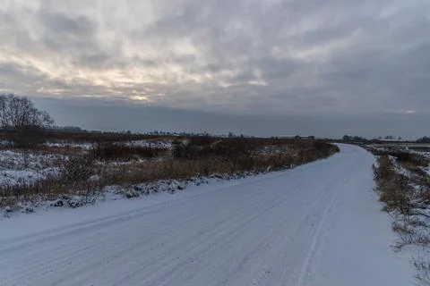 Winter landscape with sunset sky and empty snowy road. Stock Photos