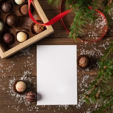 Winter layout. A clean sheet of paper box chocolates fluffy wooden background Stock Photos