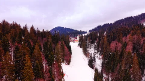 Winter light over a snowy ski slope leading to mountain lodges, Bulgaria Stock Footage 346389225