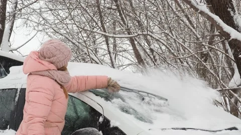 Winter Machine, covered with snow. A girl brushing snow from the car Stockbeeldmateriaal 146098693