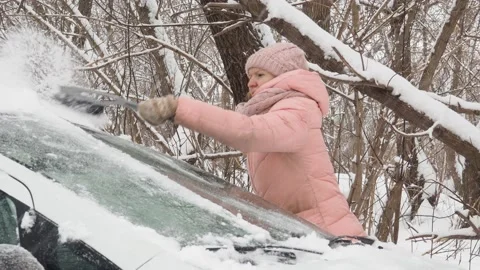 Winter Machine, covered with snow. A girl brushing snow from the car Stock Footage 146098802