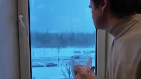 Winter. A man drinks tea looking out the window. Stock-Footage 331425693