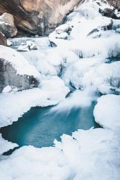 Winter mountain river under ice. Water froze and turned into icicles. Stock Photos