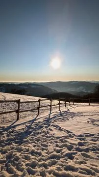 Winter mountain view with sun and snowy path at sunset. Stock Photos
