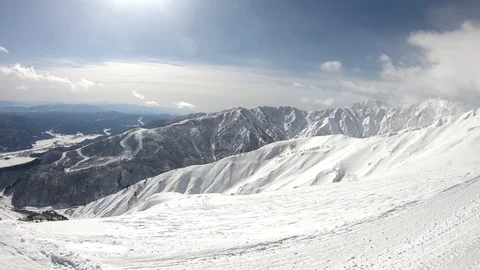 Winter mountains with snow, clouds and sunshine. Hakuba filmed from top lift Stock Footage 86560223