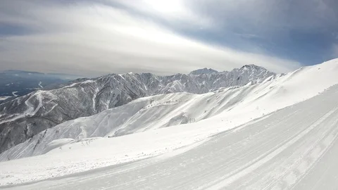 Winter mountains with snow, clouds and sunshine. Hakuba filmed from top lift Stock Footage 86560575