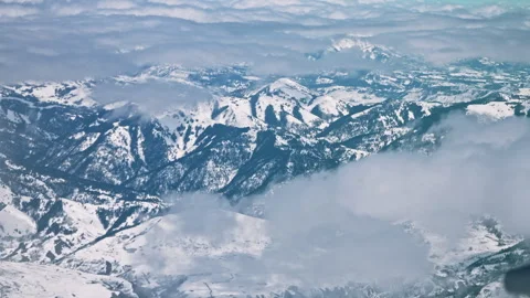 Winter Mountains through Clouds from Airplane Stock Footage 313484443