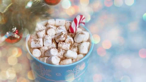 Winter mug with marshmellow against background of festive light bokeh and fir Stock Photos