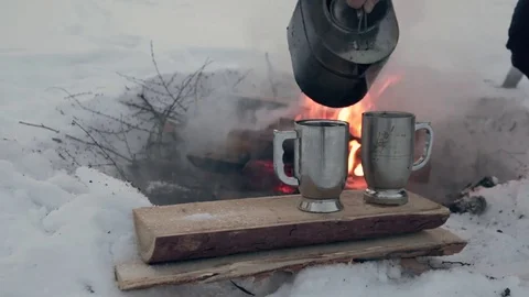 In winter, in nature, pour tea from the pot in a mug near the fire. Stock Footage 83538797