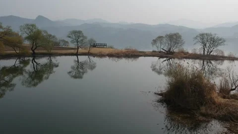 Winter over a river, reflection of trees in the water and mist over mountains Stock Footage 245833553