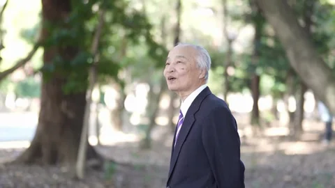 A winter park in Japan. A 78-year-old Japanese man in a suit stands and talks on 스톡 동영상 303736070