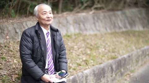 A winter park in Japan. A 78-year-old Japanese man in a suit and a down jacket Stock Footage 306420249