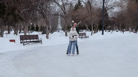 Winter park scene capturing father teaching daughter ice skating. Sharing joyful Vídeo Stock 304833185
