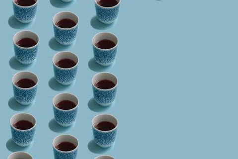 Winter pattern made of tea cups on pastel blue background.  Minimal concept a Stock Photos