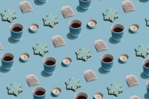 Winter pattern made of teabag, cup, candle and snowflake cookie on pastel blu Foto stock