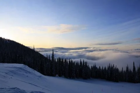 A winter photo looking down into a clouded, snow covered, forested valley Stock-Fotos