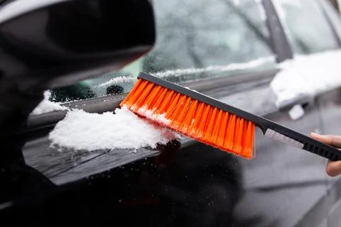 Winter problems with the car. A man cleans the car from snow with a brush Stock Photos