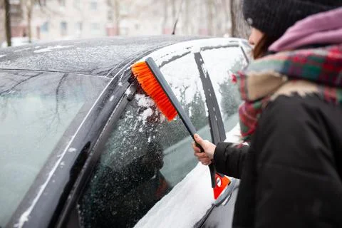 Winter problems with the car. A man cleans the car from snow with a brush Stock Photos