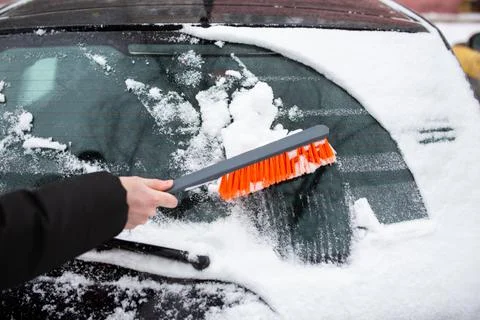 Winter problems with the car. A man cleans the car from snow with a brush Stock Photos