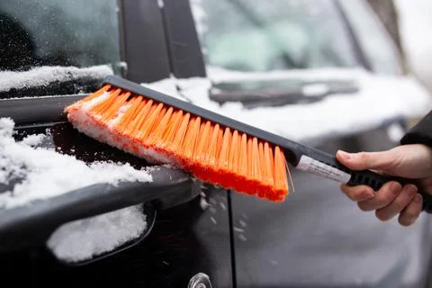 Winter problems with the car. A man cleans the car from snow with a brush Фото